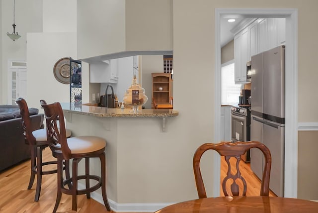 652 Spinner Cir, Mount Pleasant, SC 29464 - kitchen with appliances with stainless steel finishes, a breakfast bar, light wood-style floors, white cabinetry, and light stone counters