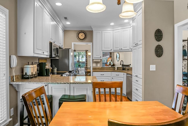 652 Spinner Cir, Mount Pleasant, SC 29464 - kitchen with stainless steel appliances, a peninsula, white cabinets, a kitchen breakfast bar, and recessed lighting