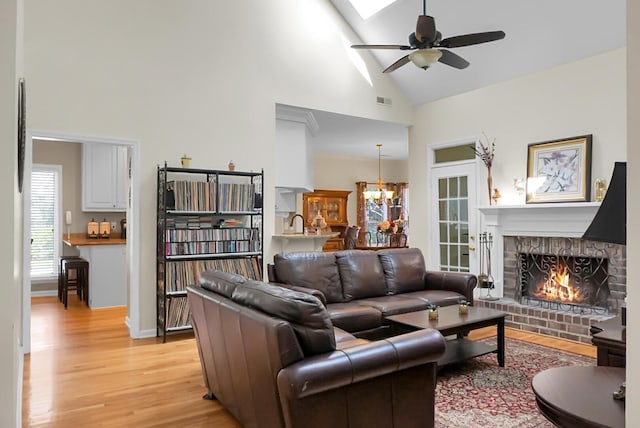 652 Spinner Cir, Mount Pleasant, SC 29464 - living room featuring high vaulted ceiling, light wood finished floors, a brick fireplace, a ceiling fan, and a chandelier
