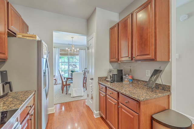 1723 Brittlebush Ln, Johns Island, SC 29455 - kitchen with stainless steel refrigerator with ice dispenser, light wood-style floors, a chandelier, brown cabinetry, and dark stone countertops