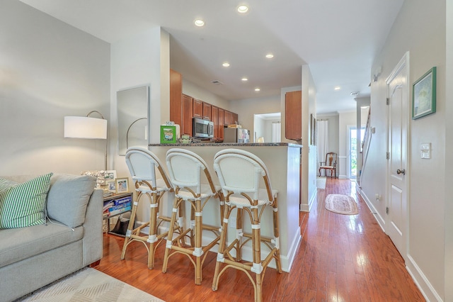 1723 Brittlebush Ln, Johns Island, SC 29455 - kitchen with brown cabinetry, light wood-style flooring, stainless steel microwave, recessed lighting, and open floor plan