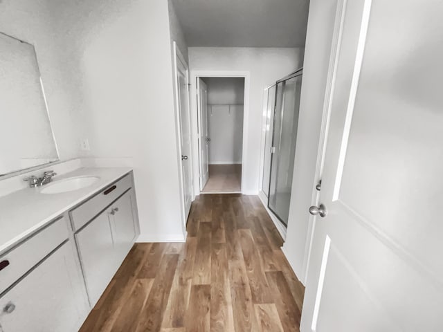 bathroom featuring an enclosed shower, vanity, and wood-type flooring