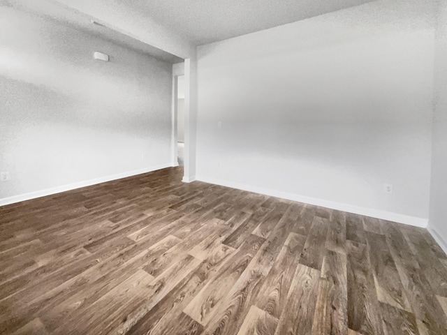 spare room with a textured ceiling and dark hardwood / wood-style floors