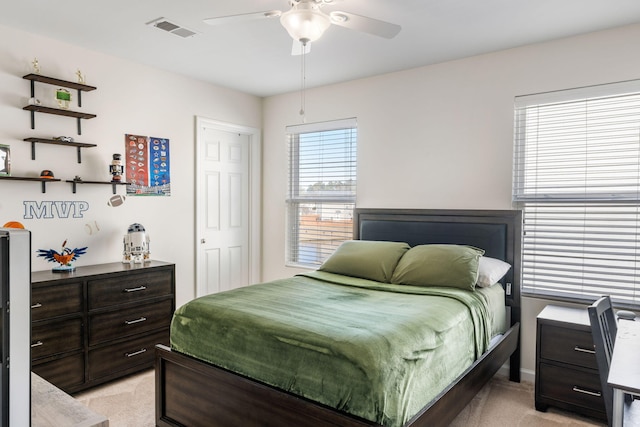 bedroom featuring visible vents, light colored carpet, and a ceiling fan