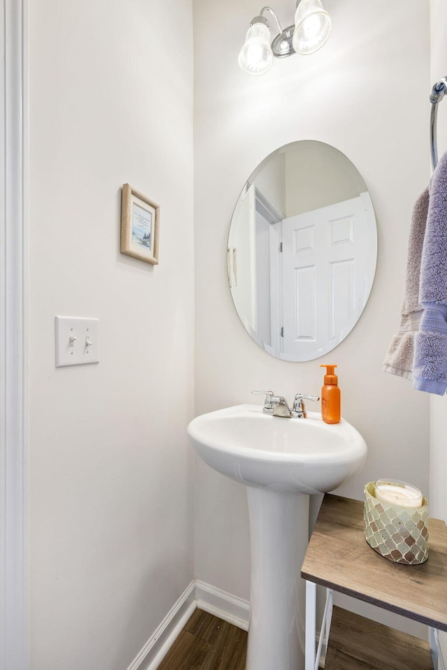 bathroom with a chandelier, baseboards, and wood finished floors