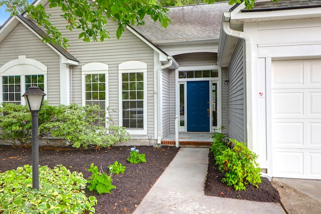 doorway to property with a garage and roof with shingles