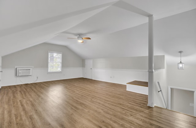 additional living space with a wall mounted air conditioner, hardwood / wood-style flooring, ceiling fan, and vaulted ceiling