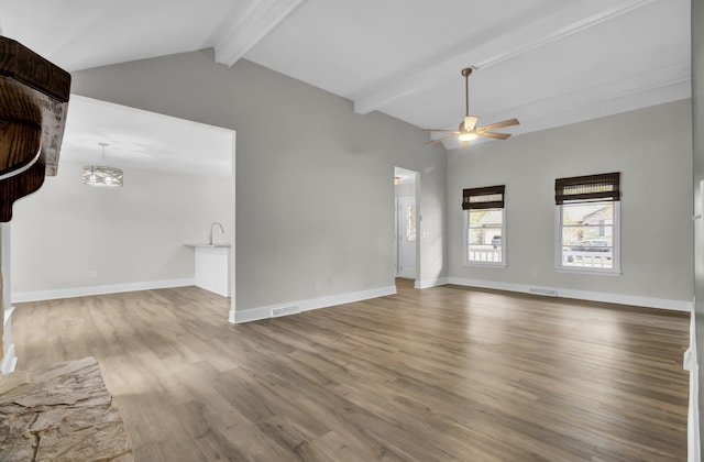 empty room featuring hardwood / wood-style flooring, vaulted ceiling with beams, and ceiling fan with notable chandelier