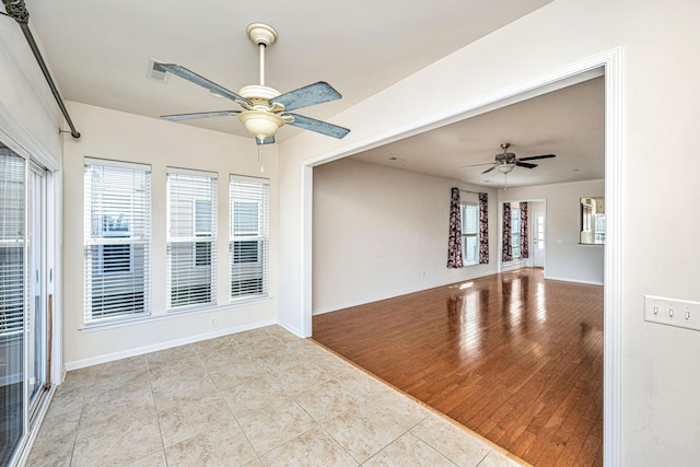 tiled empty room with ceiling fan and a healthy amount of sunlight