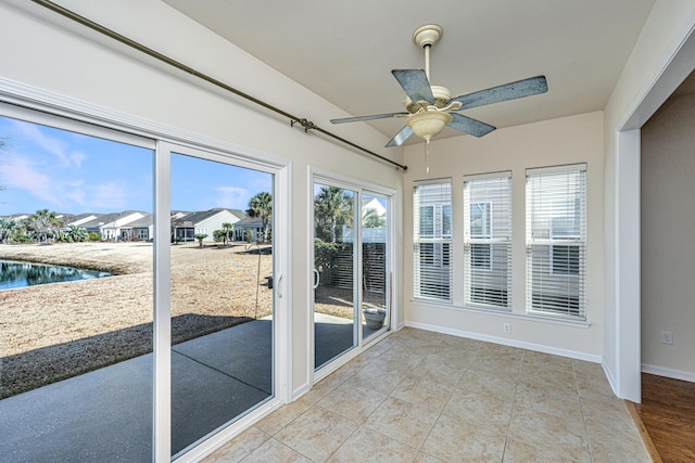 unfurnished sunroom featuring ceiling fan and a healthy amount of sunlight