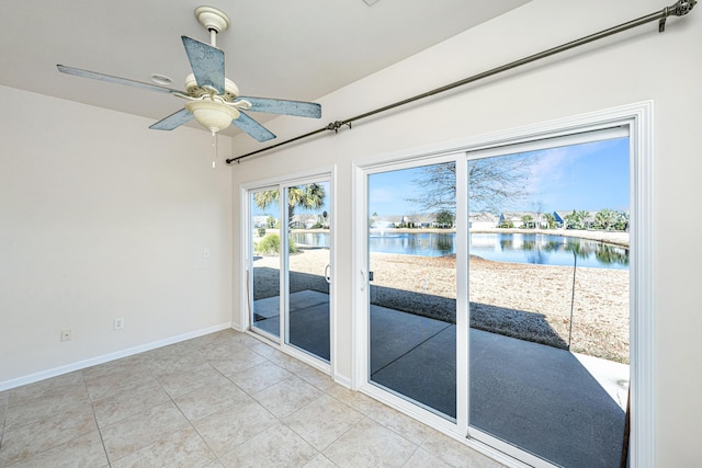 empty room featuring ceiling fan, light tile patterned floors, and a water view