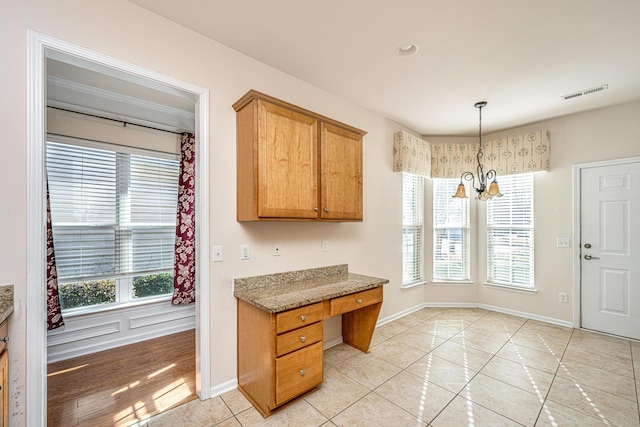 kitchen featuring an inviting chandelier, light tile patterned floors, plenty of natural light, and hanging light fixtures