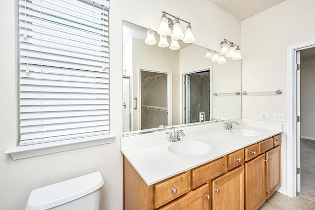 bathroom featuring toilet, vanity, and a notable chandelier