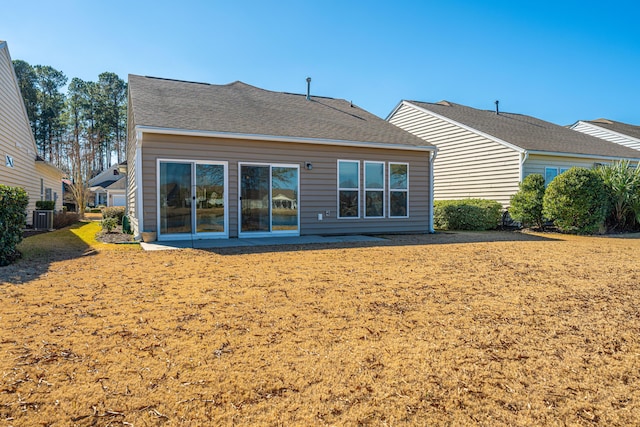 rear view of house with cooling unit and a lawn