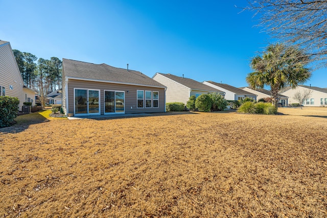 back of house with central AC and a lawn