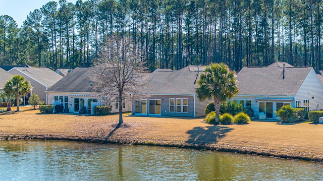 back of house with a water view and a lawn