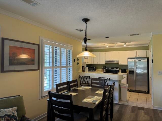 dining room featuring crown molding, a textured ceiling, and light wood-type flooring