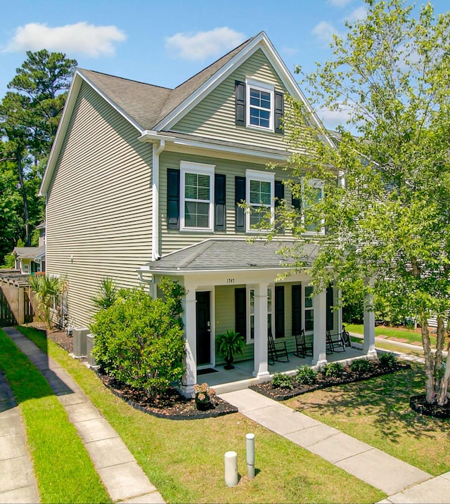 view of front of house with a shingled roof, fence, a porch, central AC, and a front yard