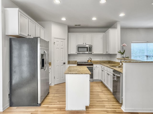 kitchen featuring a kitchen island, a sink, visible vents, light wood-style floors, and appliances with stainless steel finishes