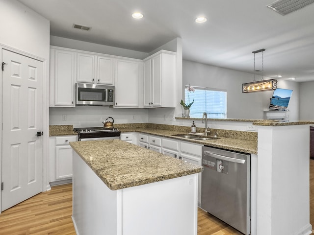 kitchen with visible vents, appliances with stainless steel finishes, a peninsula, light wood-type flooring, and a sink