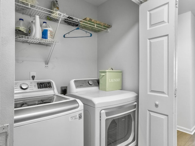 washroom featuring wood finished floors, laundry area, and separate washer and dryer