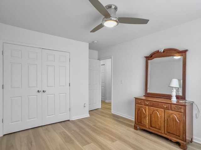 bedroom with light wood-type flooring, a ceiling fan, baseboards, and a closet