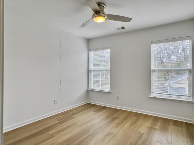 unfurnished room featuring light wood finished floors, baseboards, visible vents, and a ceiling fan