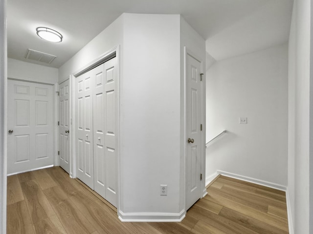 hallway with visible vents, baseboards, and wood finished floors