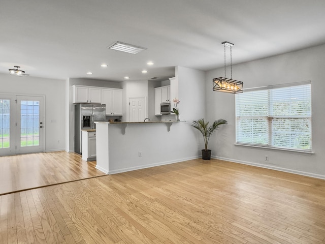 kitchen with appliances with stainless steel finishes, light wood-type flooring, open floor plan, and a breakfast bar area