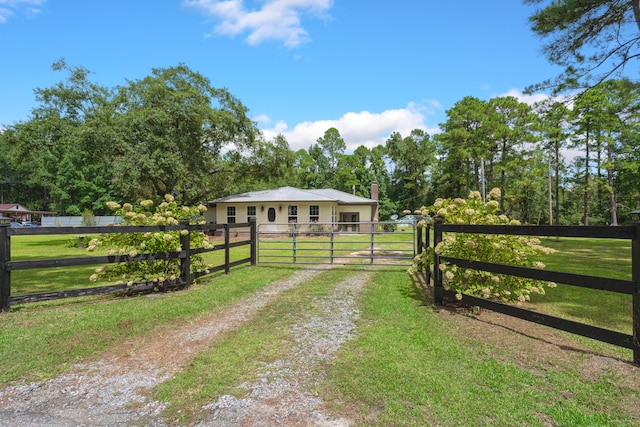 view of gate with a lawn and a rural view