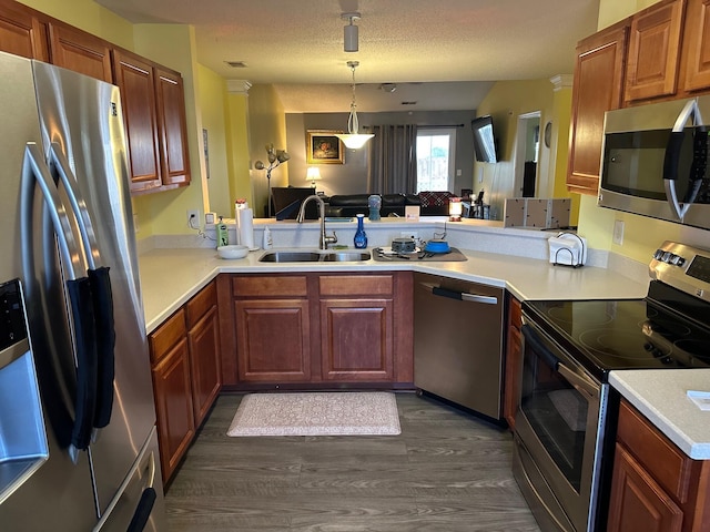 kitchen with appliances with stainless steel finishes, sink, pendant lighting, and kitchen peninsula