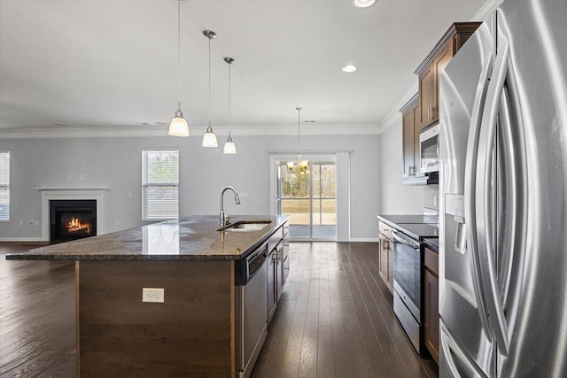 kitchen featuring a center island with sink, pendant lighting, sink, crown molding, and stainless steel appliances