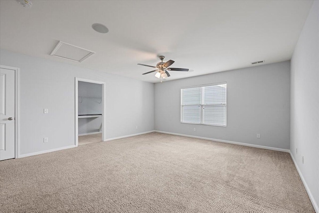 unfurnished bedroom featuring a spacious closet, ceiling fan, and carpet