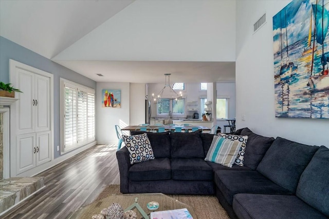 living room with wood-type flooring, vaulted ceiling, and a notable chandelier