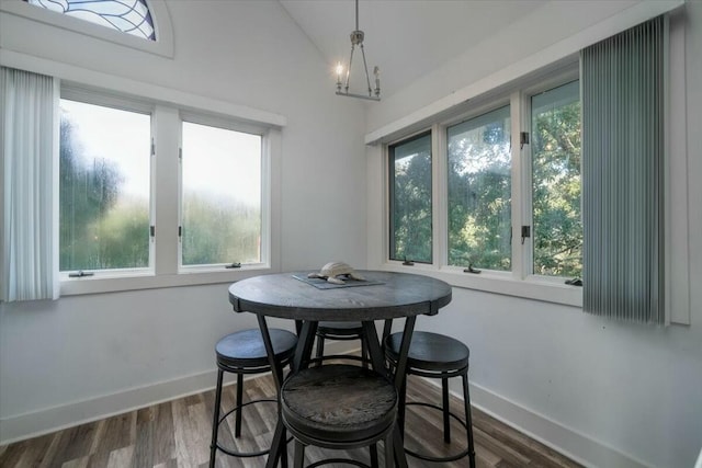 dining space with lofted ceiling, an inviting chandelier, and dark wood-type flooring