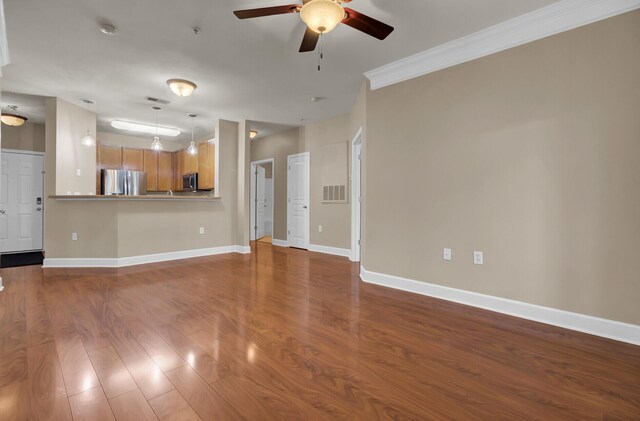 unfurnished living room featuring wood finished floors, a ceiling fan, visible vents, baseboards, and ornamental molding