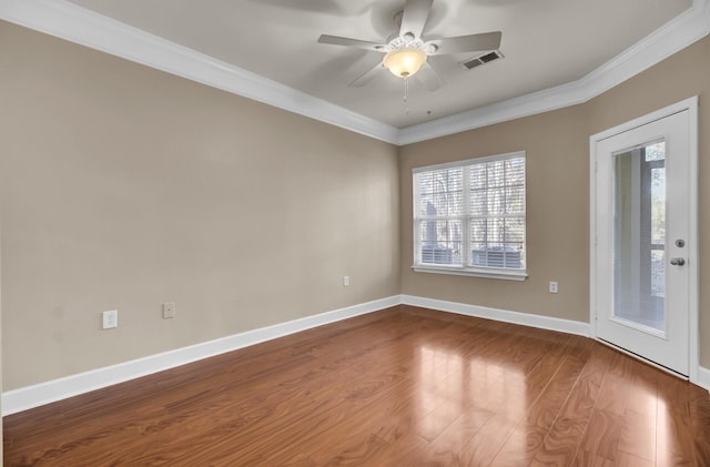 empty room featuring baseboards, visible vents, a ceiling fan, dark wood finished floors, and crown molding