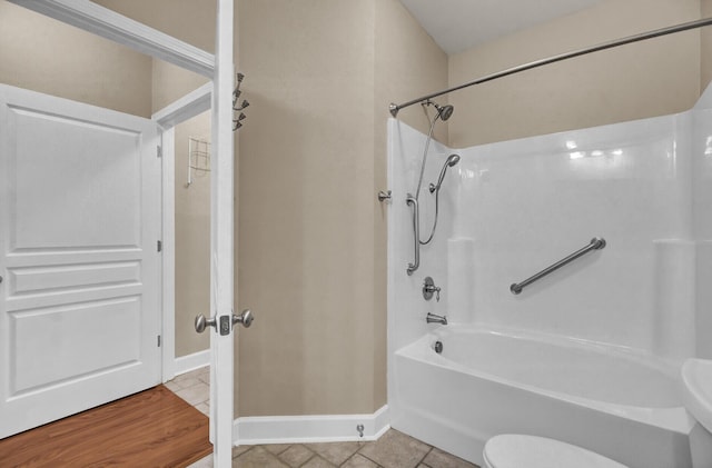 full bath featuring toilet, tile patterned flooring, baseboards, and bathing tub / shower combination