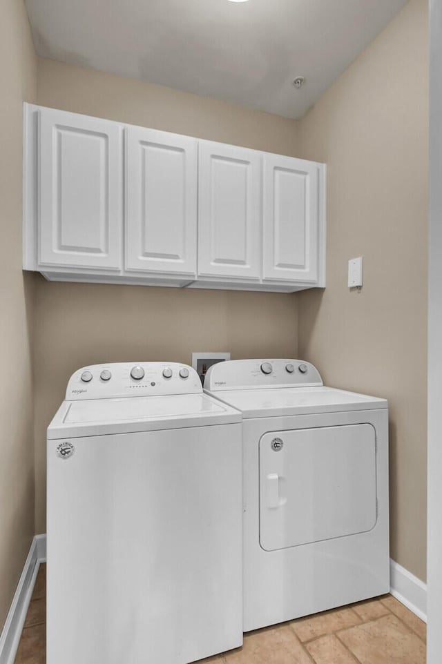 clothes washing area with cabinet space, baseboards, and independent washer and dryer