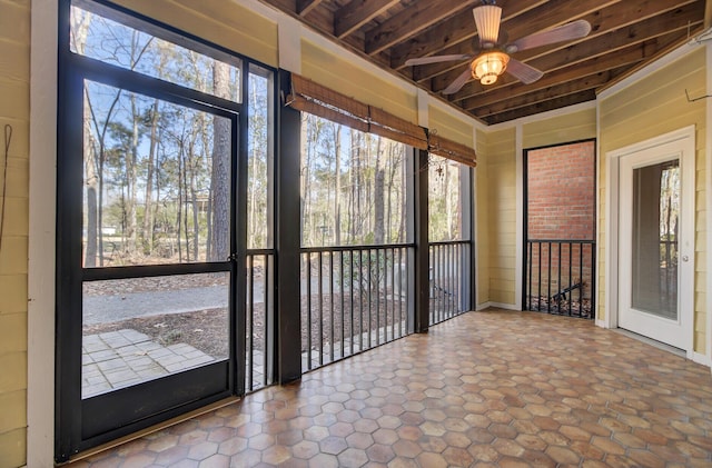 unfurnished sunroom featuring ceiling fan, beamed ceiling, and wood ceiling