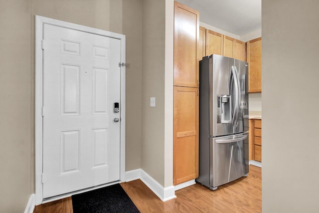 kitchen with baseboards, light wood-style flooring, light countertops, light brown cabinets, and stainless steel refrigerator with ice dispenser