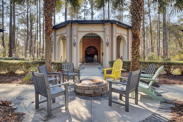 view of patio featuring an outdoor fire pit, a fireplace, and an outdoor structure