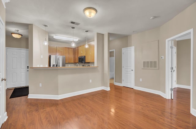 kitchen with appliances with stainless steel finishes, wood finished floors, visible vents, and baseboards