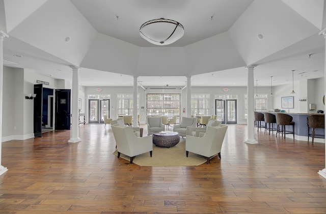 living area featuring ornate columns, plenty of natural light, and wood finished floors