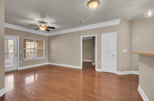 unfurnished room featuring crown molding, baseboards, and wood finished floors