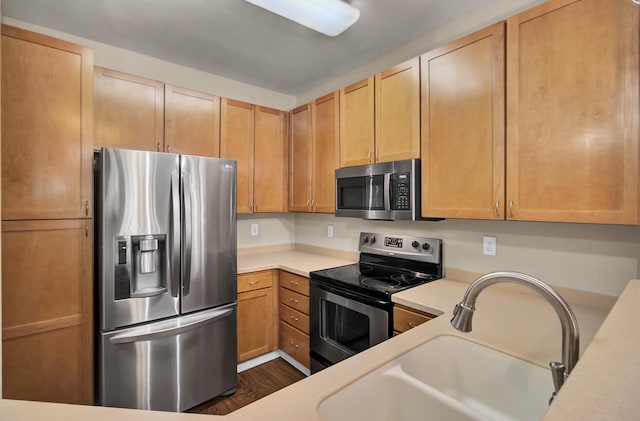 kitchen featuring stainless steel appliances, dark wood-style flooring, a sink, and light countertops