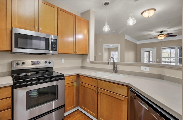 kitchen with light countertops, appliances with stainless steel finishes, a sink, and decorative light fixtures