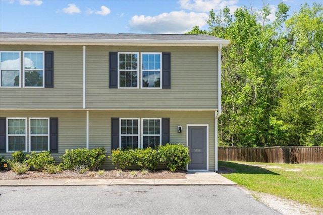 multi unit property featuring a front lawn and fence
