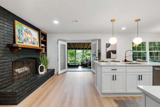 886 Friendly Cir, Charleston, SC 29414 - kitchen with a sink, white cabinetry, hanging light fixtures, light wood-style flooring, and a fireplace