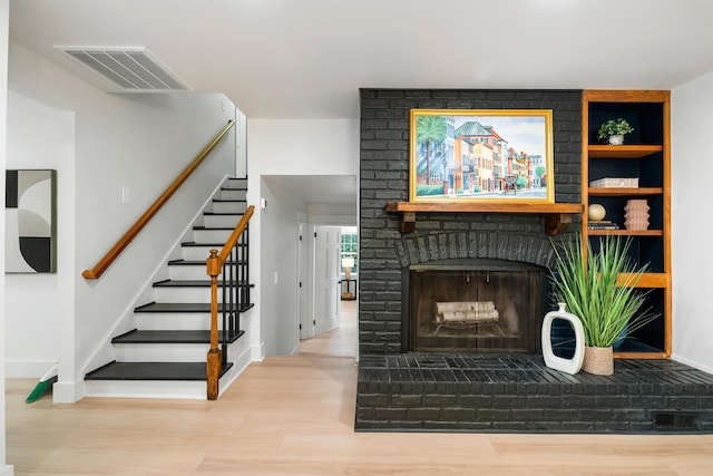 886 Friendly Cir, Charleston, SC 29414 - unfurnished living room with wood finished floors, stairway, baseboards, a brick fireplace, and built in shelves